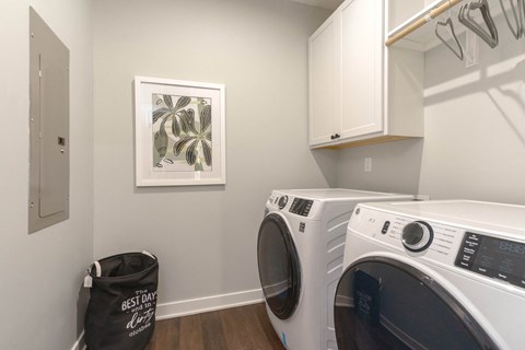 a washer and dryer in a laundry room with white cabinets and a window